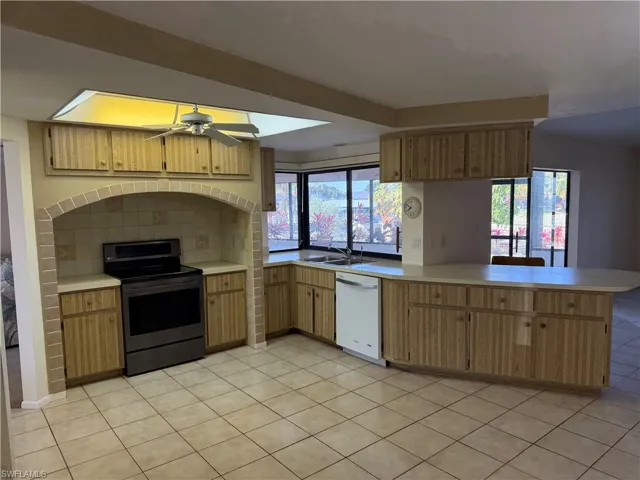 Kitchen with a peninsula, electric range, ceiling fan, light countertops, and dishwasher