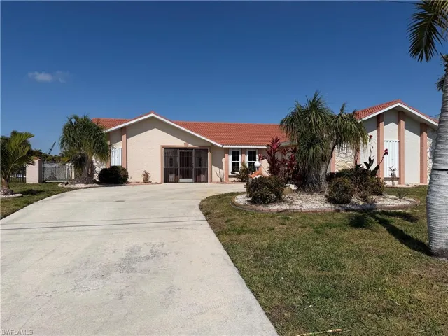 View of front of house with a tiled roof, a front yard, stucco siding, and concrete driveway