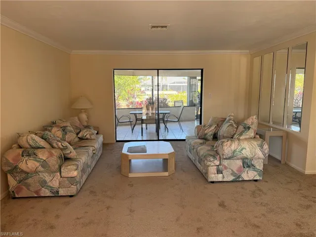 Carpeted living room with baseboards and crown molding