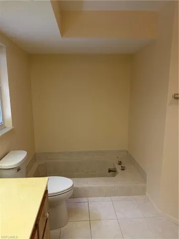Full bathroom featuring vanity, light tile patterned flooring, and a bath