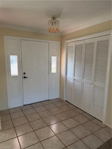 Entrance foyer with crown molding and light tile patterned flooring