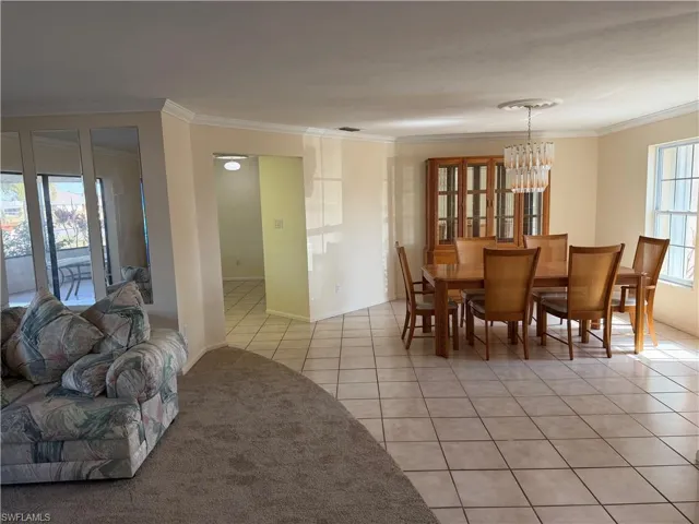 Dining area featuring light tile patterned floors, crown molding, and hanging lights