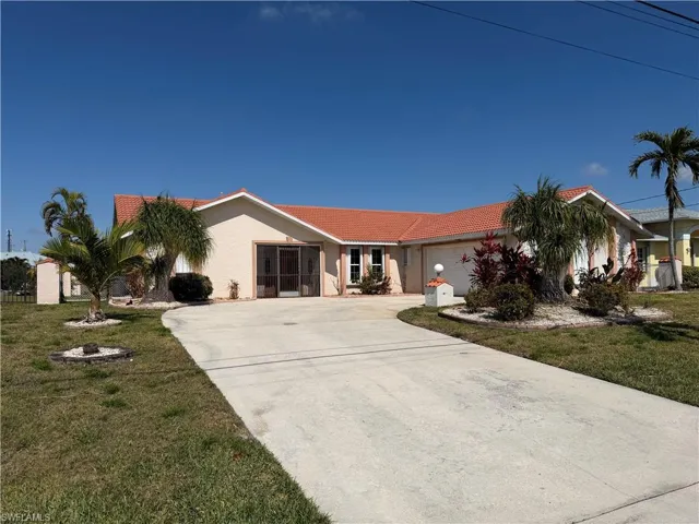 Ranch-style house with a tiled roof, stucco siding, a garage, concrete driveway, and a front lawn