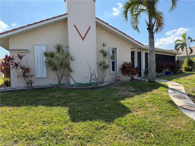 View of side of home featuring a lawn, stucco siding, and a sunroom