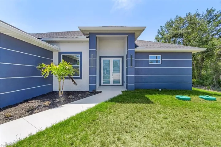 View of front of home with french doors, a front yard, stucco siding, and a shingled roof