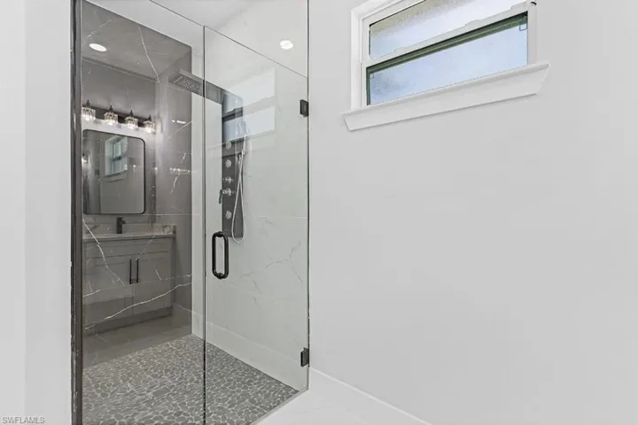 Bathroom featuring a stall shower, marble finish floors, and baseboards