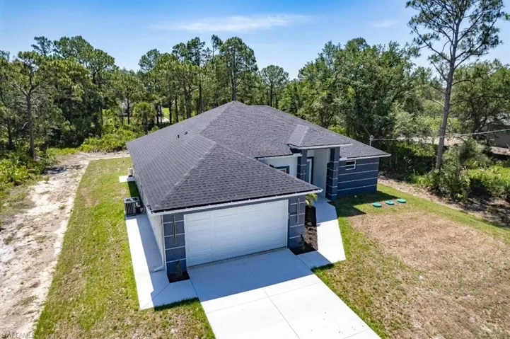 View of front facade with roof with shingles, concrete driveway, a front yard, and a garage