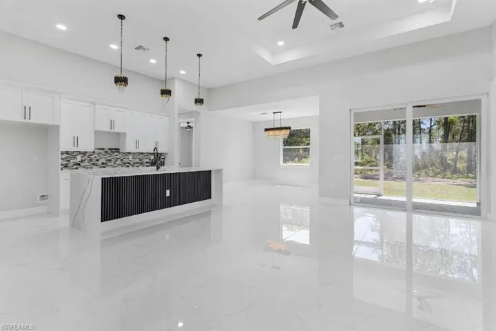 Unfurnished living room with light marble finish flooring, ceiling fan, and recessed lighting