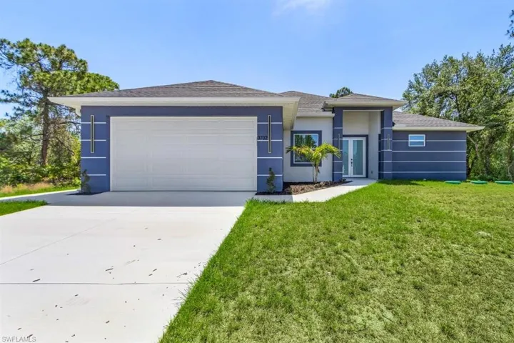View of front of home with concrete driveway, a front lawn, stucco siding, a garage, and a shingled roof