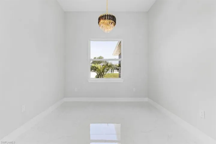 Spare room with a chandelier, marble finish floors, and baseboards
