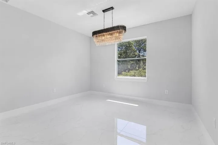 Spare room featuring marble tiled flooring, a chandelier, and baseboards