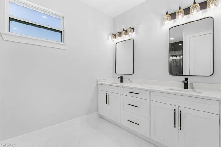 Full bathroom featuring marble finish flooring, baseboards, and double vanity
