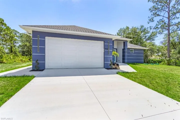 Ranch-style house with concrete driveway, stucco siding, a front lawn, and an attached garage