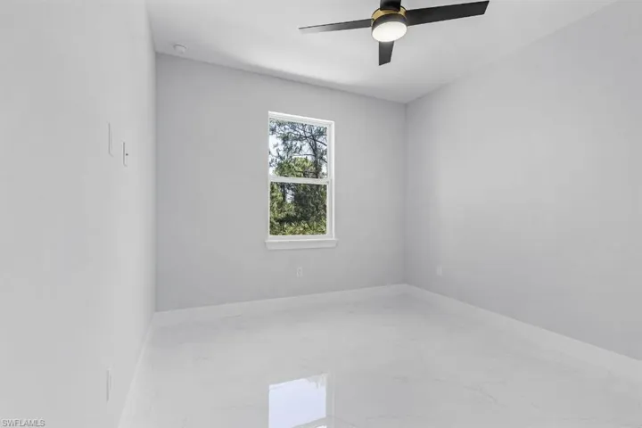 Unfurnished room with marble tiled flooring, a ceiling fan, and baseboards
