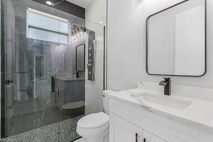 Bathroom featuring toilet, a marble finish shower, and vanity
