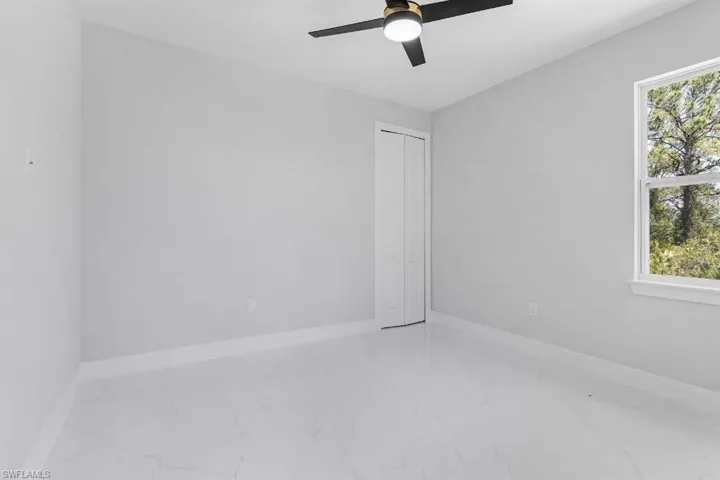 Spare room featuring marble finish floors, a ceiling fan, and baseboards