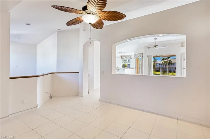 Tiled spare room featuring baseboards, ceiling fan, vaulted ceiling, recessed lighting, and arched walkways