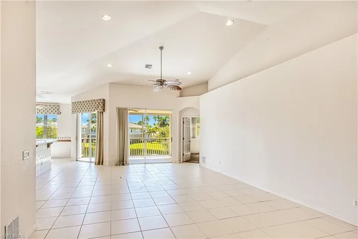 Spare room with light tile patterned floors, arched walkways, visible vents, and ceiling fan
