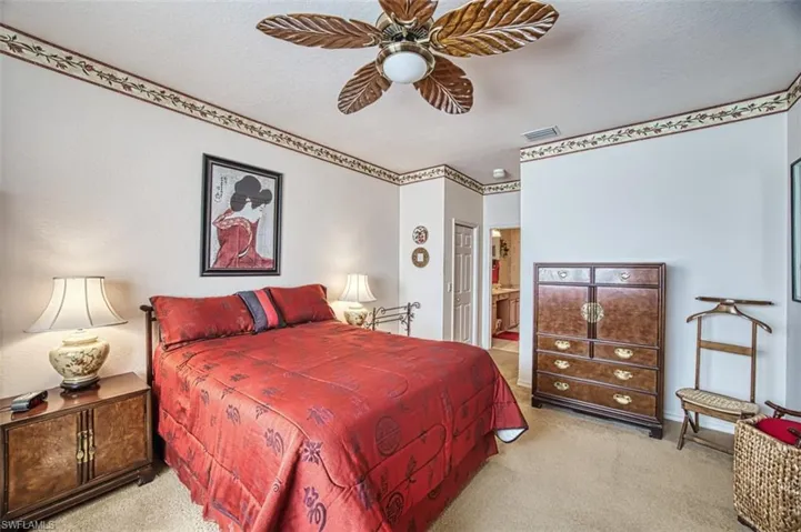 Carpeted bedroom with ceiling fan, connected bathroom, and a textured ceiling