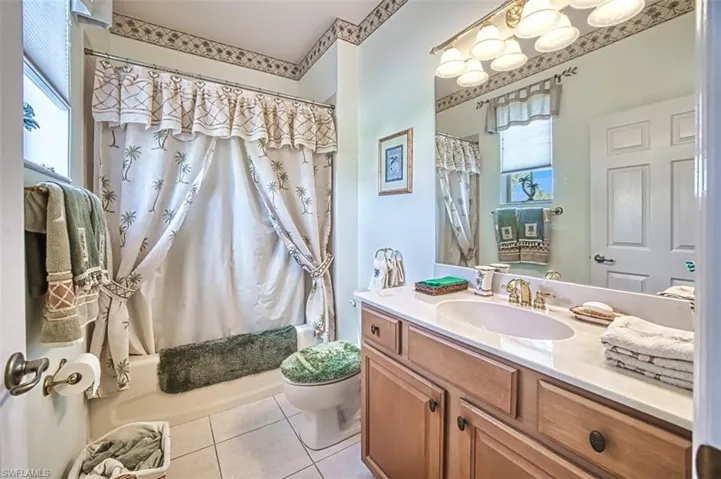 Full bathroom with vanity, tile patterned floors, toilet, and shower / tub combo with curtain