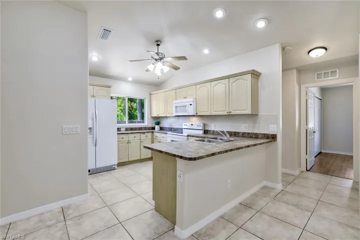 Kitchen featuring white appliances, light tile floors, and kitchen peninsula