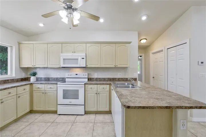 Kitchen with sink, plenty of natural light, white appliances, and kitchen peninsula
