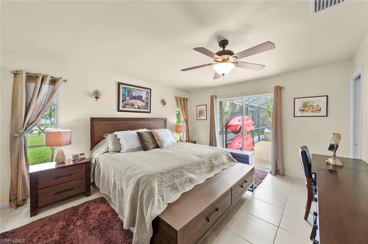 Bedroom featuring ceiling fan, access to exterior, multiple windows, and light tile patterned flooring