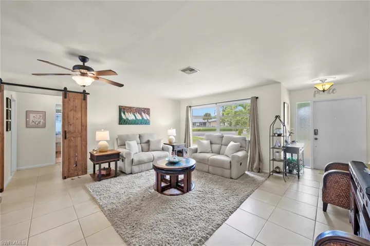 Tiled living room with ceiling fan and a barn door