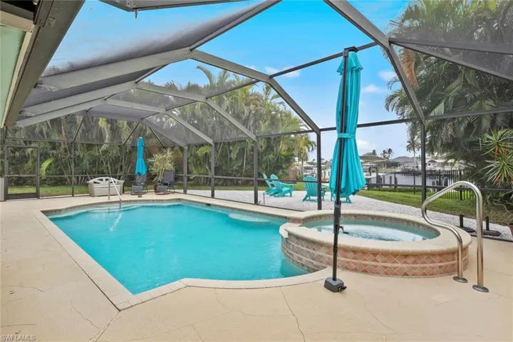View of swimming pool with a lanai, a water view, an in ground hot tub, and a patio