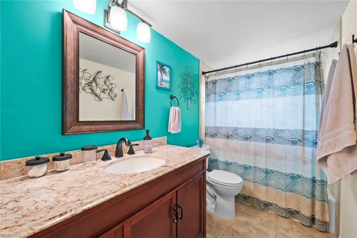 Bathroom with tile patterned flooring, toilet, vanity, and a shower with shower curtain