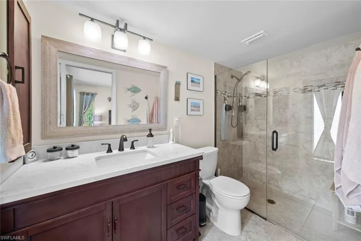 Bathroom with toilet, vanity, tile patterned flooring, and a shower with door