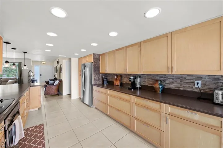 Kitchen featuring decorative light fixtures, light brown cabinetry, and stainless steel appliances