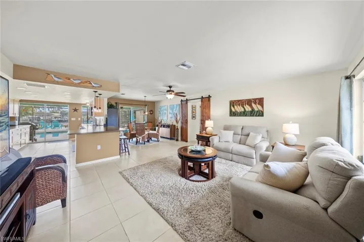 Tiled living room with ceiling fan and a barn door