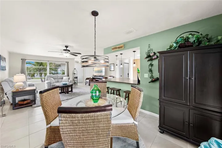 Dining space featuring ceiling fan with notable chandelier and light tile patterned floors