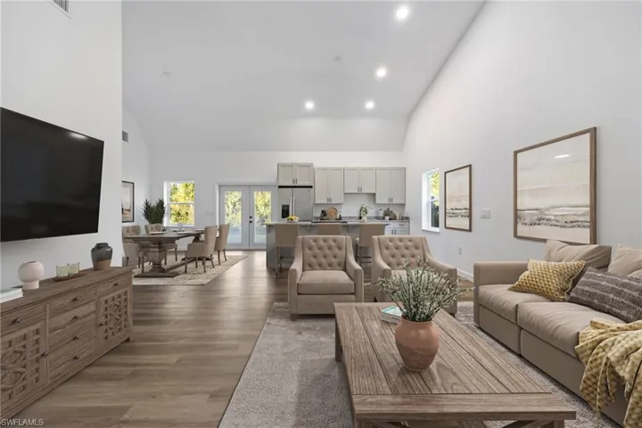 Living room with high vaulted ceiling, french doors, dark wood finished floors, and recessed lighting