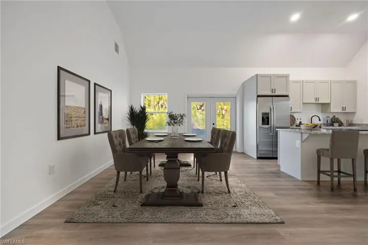 Dining room featuring french doors, light wood-type flooring, and high vaulted ceiling