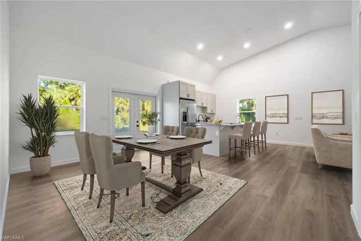 Dining space with high vaulted ceiling, recessed lighting, french doors, and dark wood-style flooring
