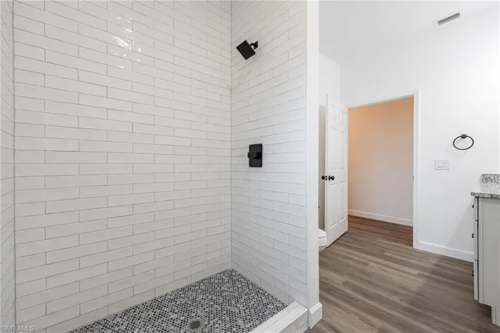 Bathroom featuring a stall shower, vanity, and dark wood finished floors