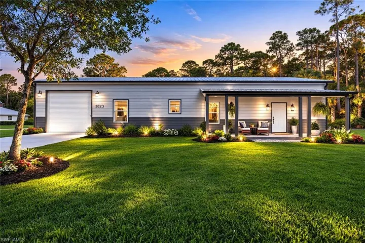 View of front facade featuring a metal roof, a front lawn, an attached garage, a porch, and driveway