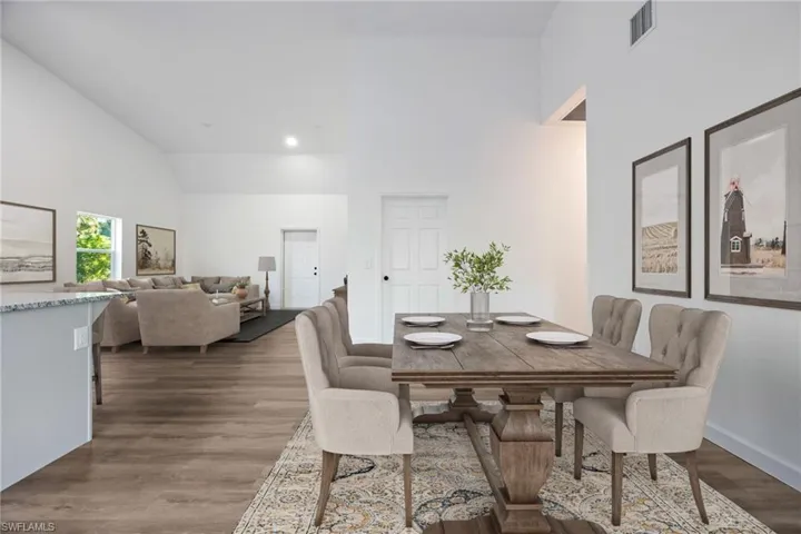 Dining area with high vaulted ceiling, dark wood-type flooring, and recessed lighting