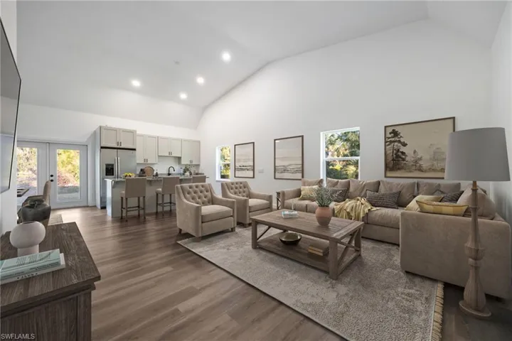 Living area featuring high vaulted ceiling, recessed lighting, dark wood finished floors, and french doors