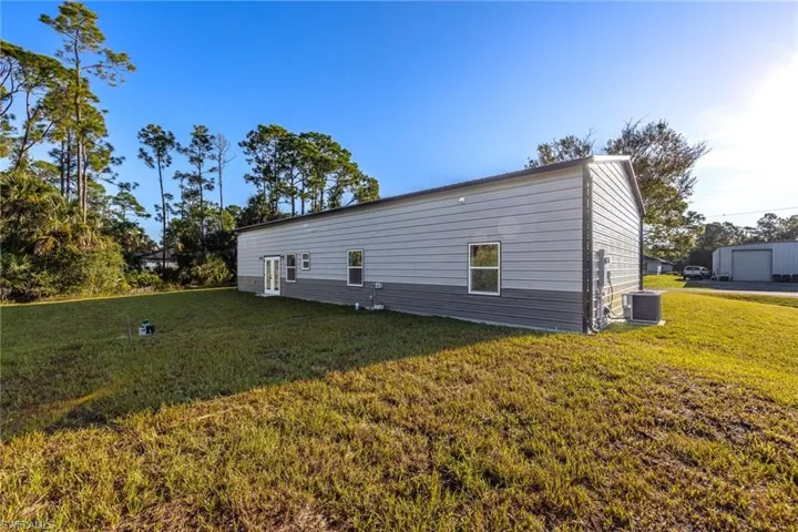 View of property exterior featuring a lawn and a central AC unit