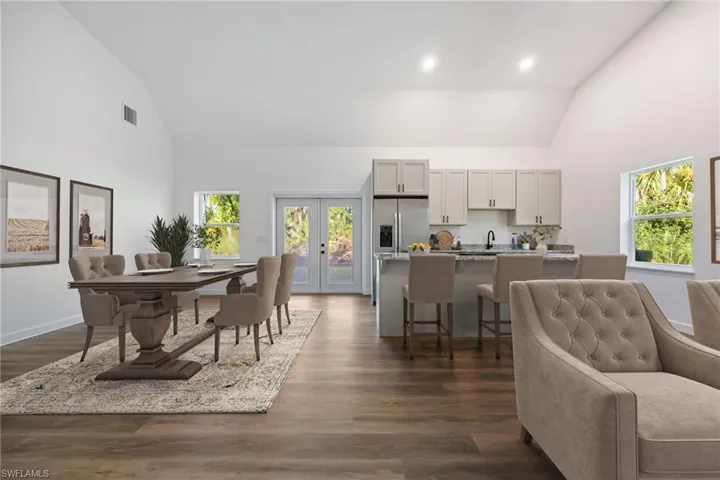 Dining room with high vaulted ceiling, dark wood-style flooring, french doors, and recessed lighting