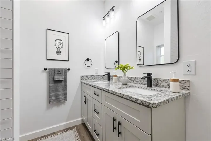 Bathroom with double vanity and dark wood-style flooring