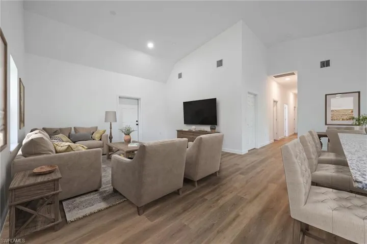 Living area with wood finished floors, high vaulted ceiling, and recessed lighting