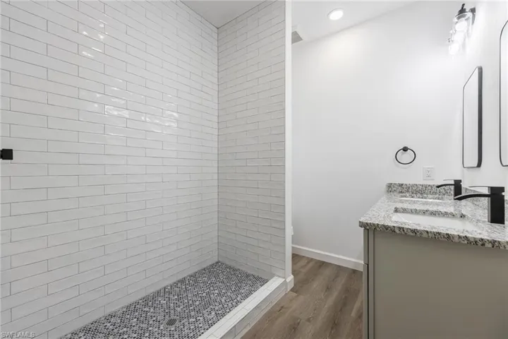 Bathroom featuring a stall shower, double vanity, and dark wood finished floors