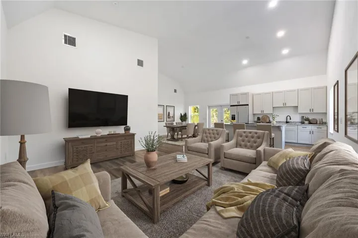 Living room with high vaulted ceiling, wood finished floors, and recessed lighting