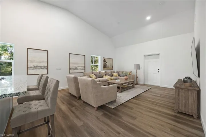 Living room featuring high vaulted ceiling, dark wood-type flooring, and recessed lighting