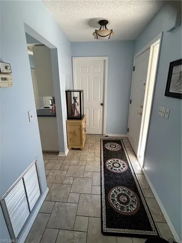 Doorway with a textured ceiling and light tile patterned floors
