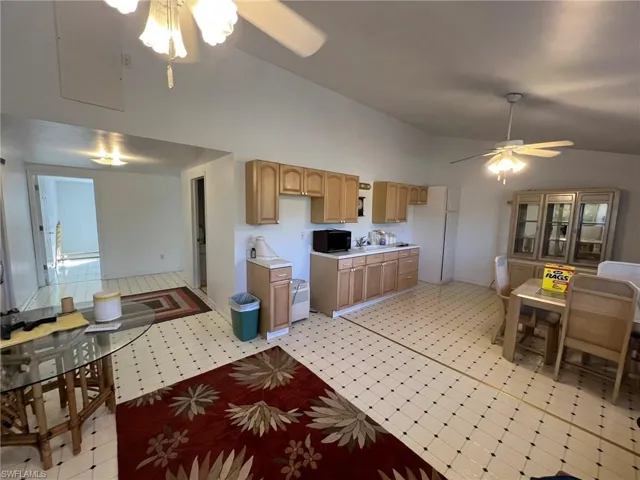 Kitchen featuring light floors, a ceiling fan, light countertops, freestanding refrigerator, and light brown cabinetry